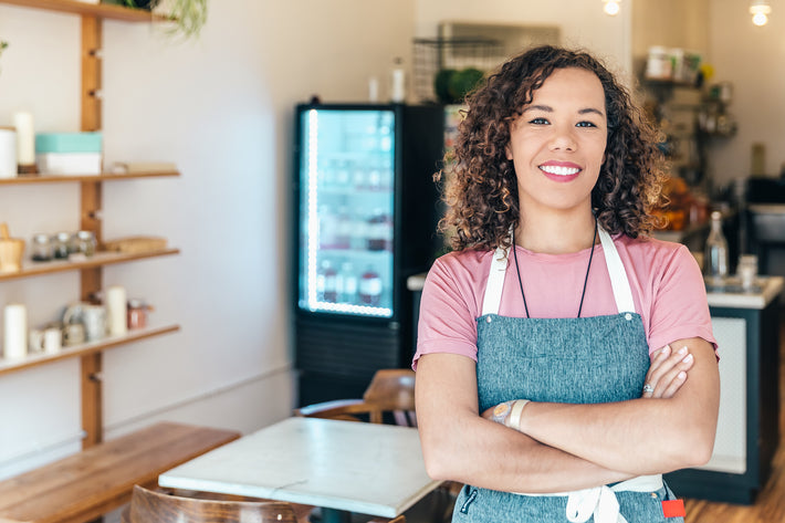 a-barista-smiles-proudly-stood-in-her-cafe - Sterilamo
